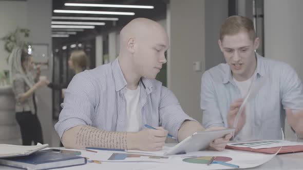 Stressed Man Showing Diagrams and Talking To Colleague