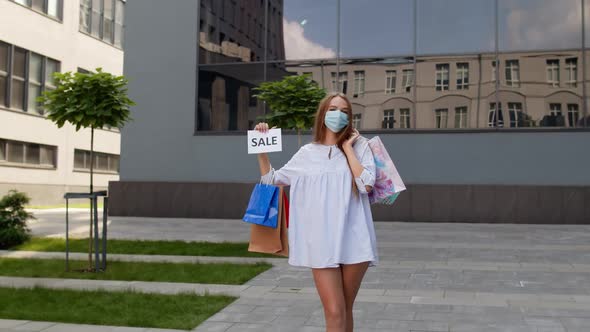 Girl in Protective Mask with Shopping Bags Showing Sale Word Inscription During Covid-19 Pandemic