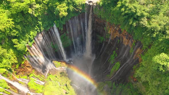 Aerial view of Tumpak Sewu Waterfall with a scenic rainbow, Indonesia.