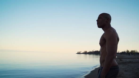 Athletic man meditating on a beach during sunset