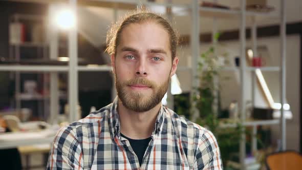 Young Bearded Guy Standing in Contemporary Office Room and Looking into Camera