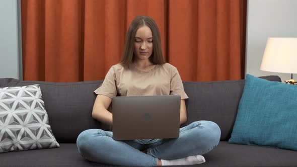 Young Woman Using Laptop Checking Email News Online Sitting on Sofa Searching for Friends in