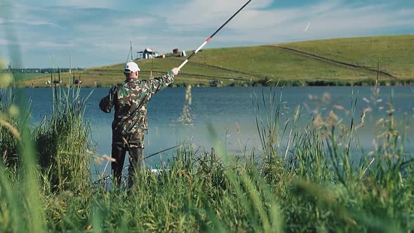 Fisherman Put a Line Out with a Fishing Pole Into the Lake