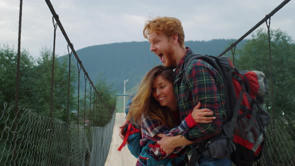 Overjoyed Travelers Couple Cheering on Mountain Bridge