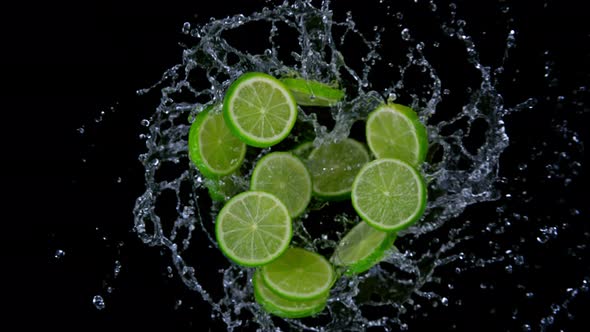 Super Slow Motion Shot of Rotating Exploded Lime Slices with Splashing Water on Black at 1000Fps