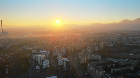 Aerial drone view of Brasov at sunrise, Romania. Roads with cars, residential buildings, yellowed tr