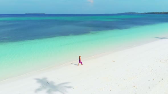 Aerial Slow motion: woman walking on white sand beach turquoise water tropical coastline
