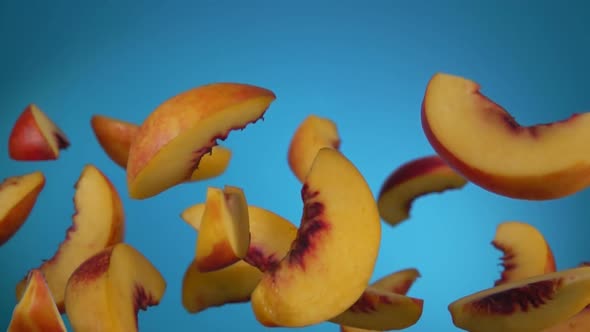 Closeup of the Peach Slices Bouncing on the Blue Background
