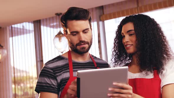 Smiling waiter and waitress using digital tablet