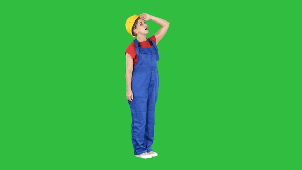 Engineer woman in yellow helmet looking up amazed at a