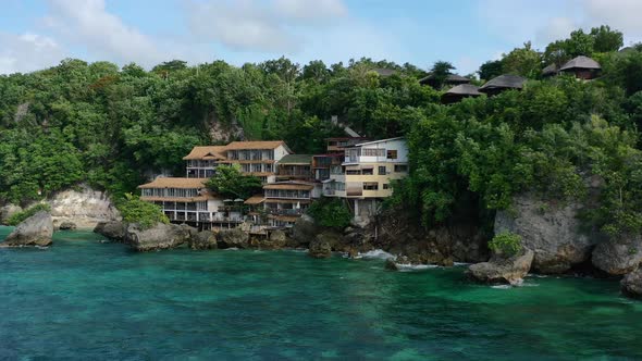 turquoise ocean waterfront hotel on Bali Island cliff in Uluwatu on sunny day, aerial