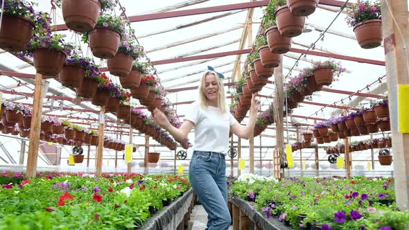 woman Florist farmer in a good mood dancing in a greenhouse