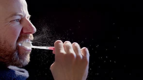 SLOW MOTION BACKLIT - A man brushing teeth sending many particles into the air