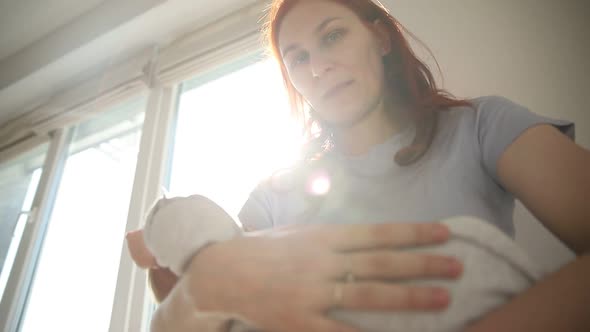 Ginger Woman Mother Holding Her Newborn Baby Standing By the Window