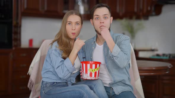 TV POV of Absorbed Millennial Couple Watching Movie Eating Popcorn