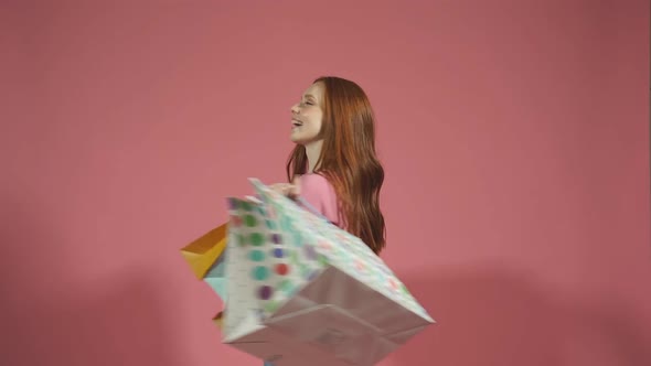 Cheerful Lady Poses with Colorful Shopping Bags on an Isolated Yellow Background in the Studio