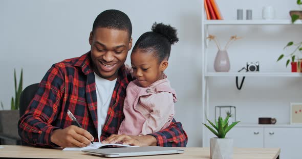 Afro American Man Father Teacher Holding Little Girl Daughter Teaching Child to Write Playing