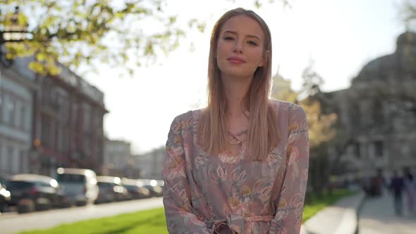 Portrait of Lovely Caucasian Woman Wearing Dress Smiling While Walking in Downtown on Sunny Summer