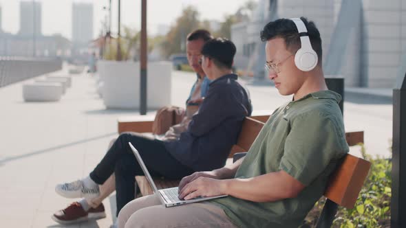 Asian Man Working on Laptop Outdoors