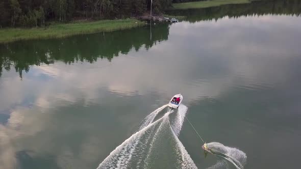 Athletic young man wakeboarding when a boat is pulling him speed. Doing tricks, jumps and curves. Ae