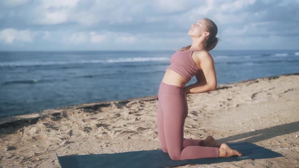 Woman Does Yoga Exercises Stretches at Morning with View on Ocean Slow Motion