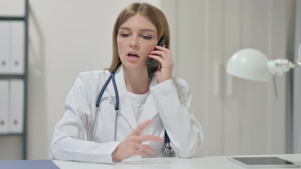 Young Female Doctor Talking on Smartphone at Work 