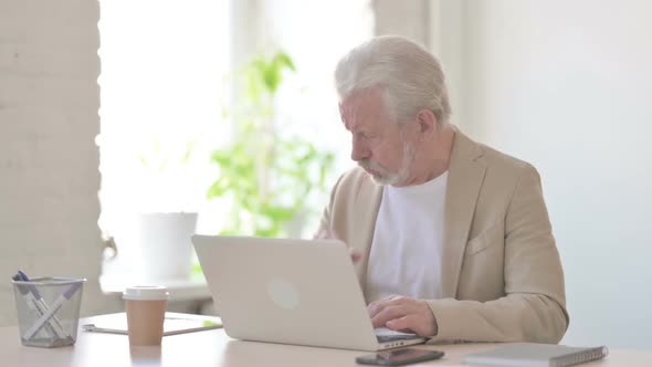 Old Man Coughing While Using Laptop in Office