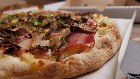 One Mushrooms and Bacon Pizza on Black Slate Platter and Wooden Table