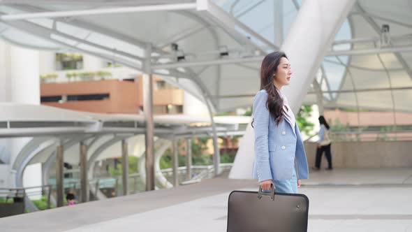 4K Asian business woman checking time on hand watch while walking in railway station in the morning.