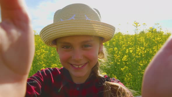 Joyful Child Looking at Camera and Walking Through Rapeseed Field