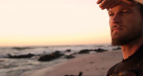 Male surfer shielding eyes in the beach 4k