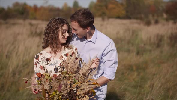 Positive Young Happy Loving Couple. Young Woman Holding Flowers in Hands.