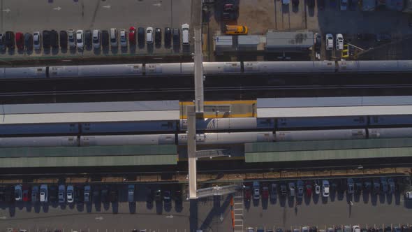 Top Down Aerial Pan of Trains Stopped at Station and Parking Lot in Long Island