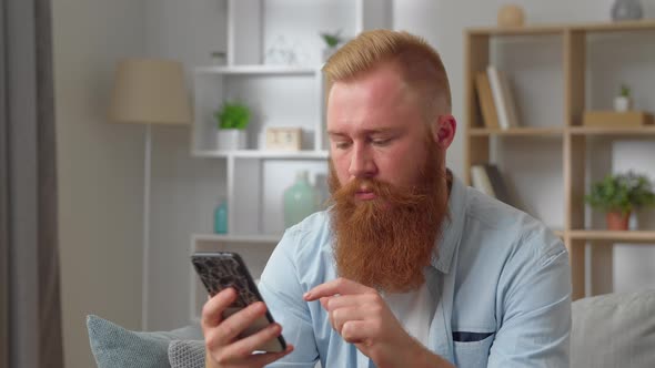 Frustrated Young Redhear Man Looking at Smartphone Screen Feeling Disappointed with Received Bad