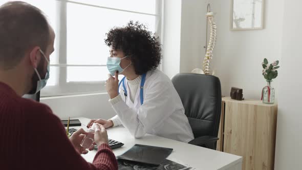 Doctor and Patient in Face Mask Talking in a Medical Consultation in a Clinic