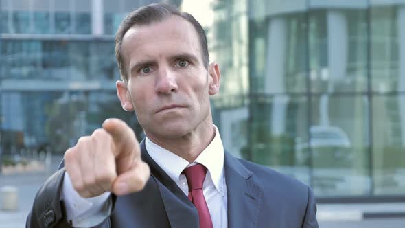 Middle Aged Businessman Pointing with Finger Outside Office