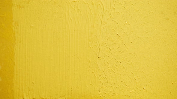 Painting Walls with Yellow Paint Using Roller Closeup