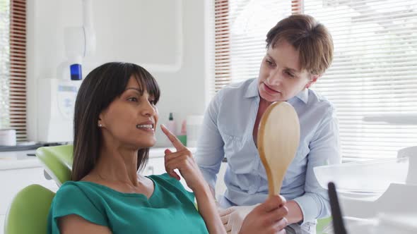 Caucasian female dental nurse talking with female patient at modern dental clinic