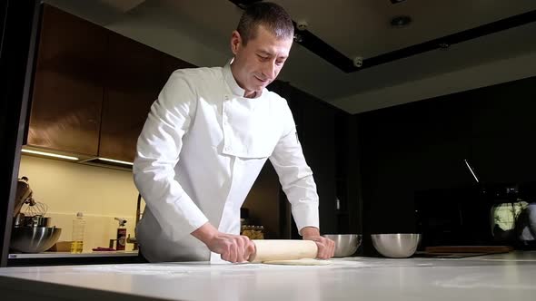 Closeup chef rolling pizza dough. Preparation of pizza dough. Italian cuisine