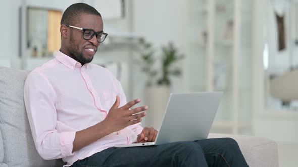Attractive African Man Doing Video Call on Laptop at Home