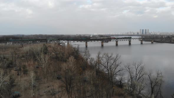 Long Freight Train on The Bridge Crossing River in The Industrial City