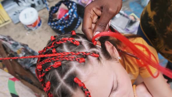 Process of Weaving African Braids with Red Kanekalon Outdoor Zanzibar Africa