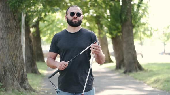 Disabled Man Folding a White Cane in a Park
