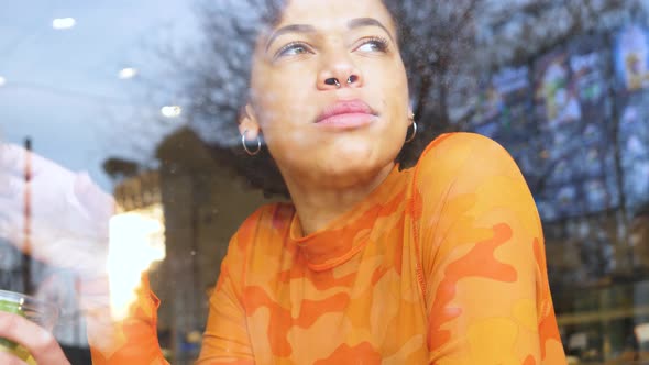 young beautiful curly hair black woman sitting cafeteria drinking from reusable cup