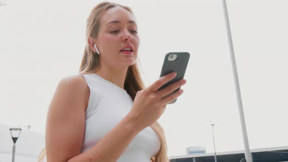 Slow motion young woman outdoor using smartphone listening music