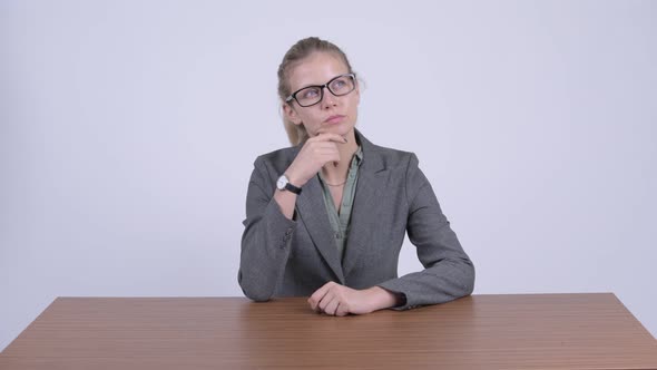 Young Beautiful Blonde Businesswoman Thinking While Sitting Behind Desk