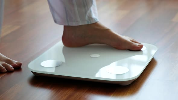 Crop woman standing on digital weight scales