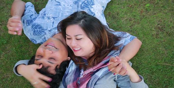 Young Couple Relaxing On Lawn In A City Park