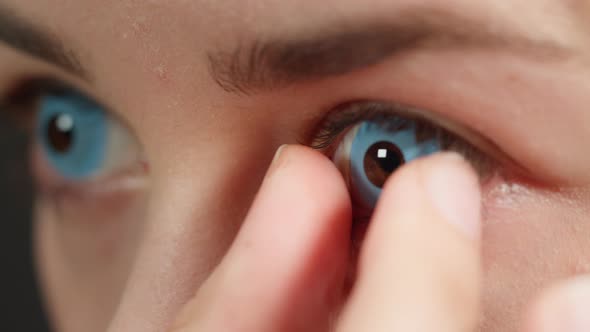 Closeup of a Browneyed Young Woman Taking Off the Blue Lens with Fingers