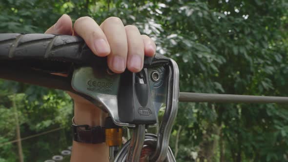 Hands Holding Carabiner On Zip Line In Forest